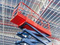 Scissor lift platform with hydraulic system elevated towards a factory roof with construction workers, Mobile aerial work platform